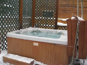 Relax in the hot tub, surrounded by a serene outdoor setting.