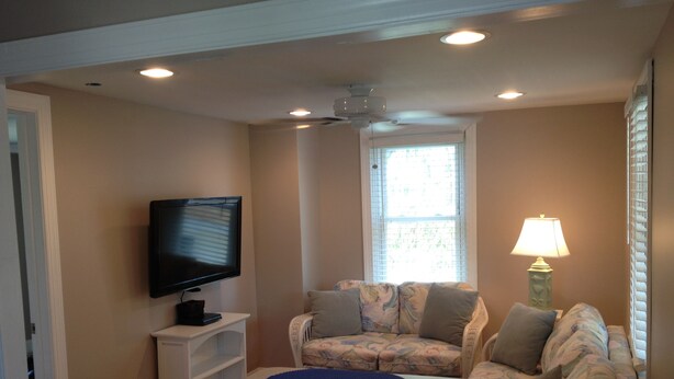 A compact living room with a flat-screen TV, a ceiling fan, and a window with blinds. - 🥇PRIVATE COASTAL COTTAGE - Single Private - Central Air, Xfinity Cable, WIFI🏖 (Wildwood Crest)