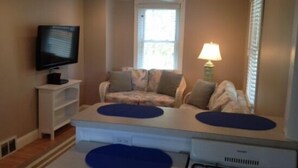 A living room with a sofa, a TV, a lamp, and a window. - 🥇PRIVATE COASTAL COTTAGE - Single Private - Central Air, Xfinity Cable, WIFI🏖 (Wildwood Crest)