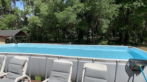Una piscina con cuatro sillas reclinables y una manguera.