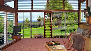 Una habitación con una cama grande, televisión y vistas a un jardín exuberante.