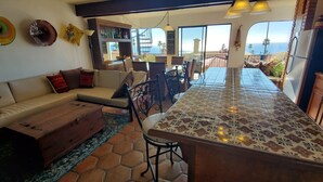 Un vaste espace de vie comprenant un grand îlot de cuisine, un canapé et une table à manger.