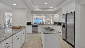 A spacious kitchen with white cabinetry, granite countertops, stainless steel appliances, and a large island. - Stunning Beach Home! 3 Oceanfront Masters w/ ensuite Baths! Panoramic Views!  (Myrtle Beach)