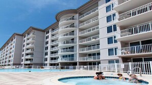 A multi-story hotel with balconies, a swimming pool, and a tiled deck area. - Island Princess 214-Beautiful Updated 2Bd Beachfront Condo-Free Beach Service (Fort Walton Beach)