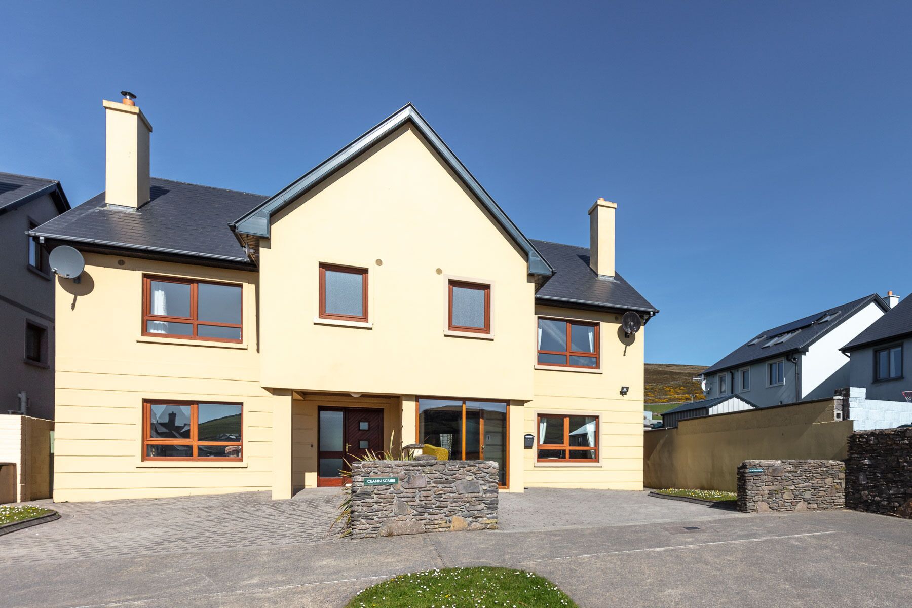 A two-story house with a gabled roof, stone pillars, and a front entrance.