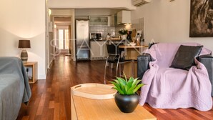En moderne stue med en sofa, et sofabord og en potteplante. I baggrunden er der et spiseområde med et bord og stole.