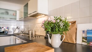 Et køkken med en hvid vase med blomster, en træskærebræt og en brun papirspose på bordet.