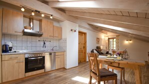 Una cocina moderna con armarios de madera, horno empotrado y un comedor con mesa y sillas de madera.