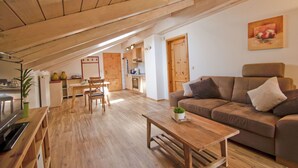 Amplia sala de estar con techo de madera, un sofá, una mesa de centro y una mesa de comedor con sillas.