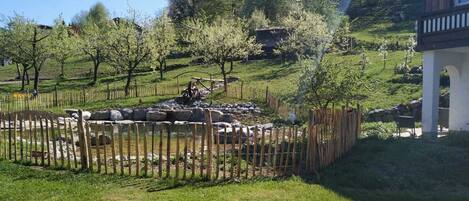 Un jardin clos, agrémenté d’un petit étang, entouré d’arbres et d’une construction en pierre.