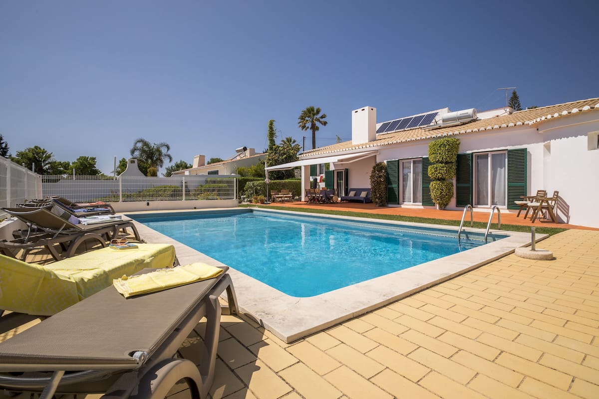 Una piscina con sillas de descanso y un patio cubierto.