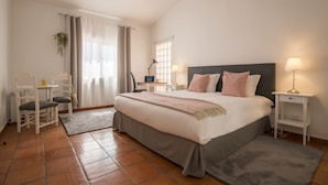 A bedroom with a large bed, bedside tables, a desk, and a chair.