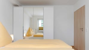 A bedroom with a bed, a wardrobe, and a mirror. - Stader Sand - House Lighthouse (Esens)