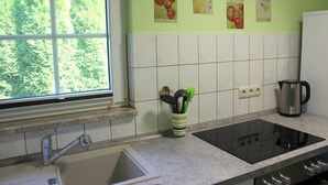 A kitchen with a window, a sink, a stove, and a coffee maker. - Vacation cottage Bley, Germany (Ahrenshoop)
