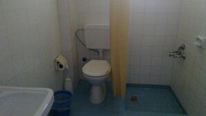 Et lille badeværelse med toilet, blå gulv, hvid vask og badeforhæng.