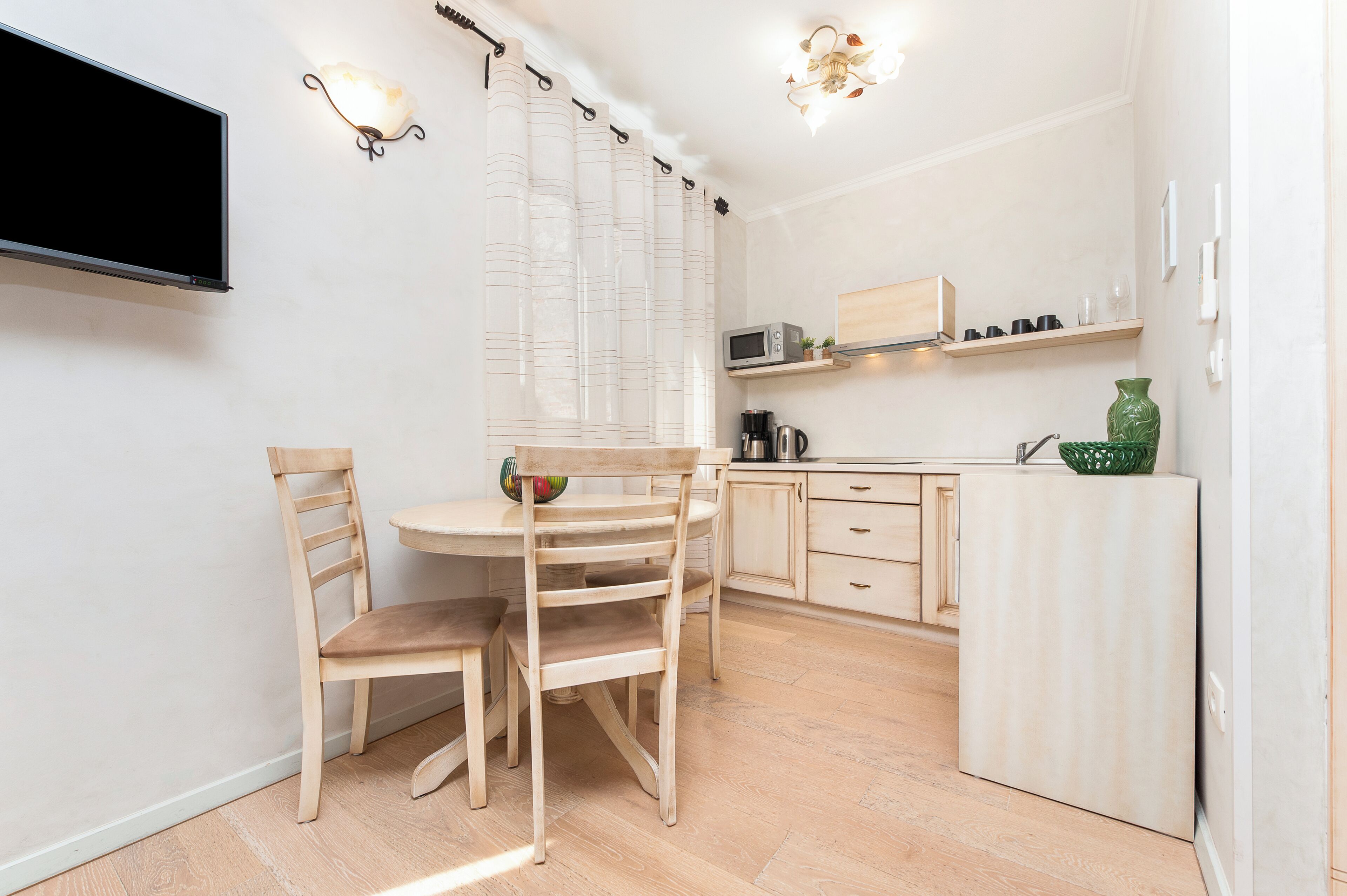 Una cocina pequeña y bien iluminada con una mesa y sillas, un microondas y una cafetera.