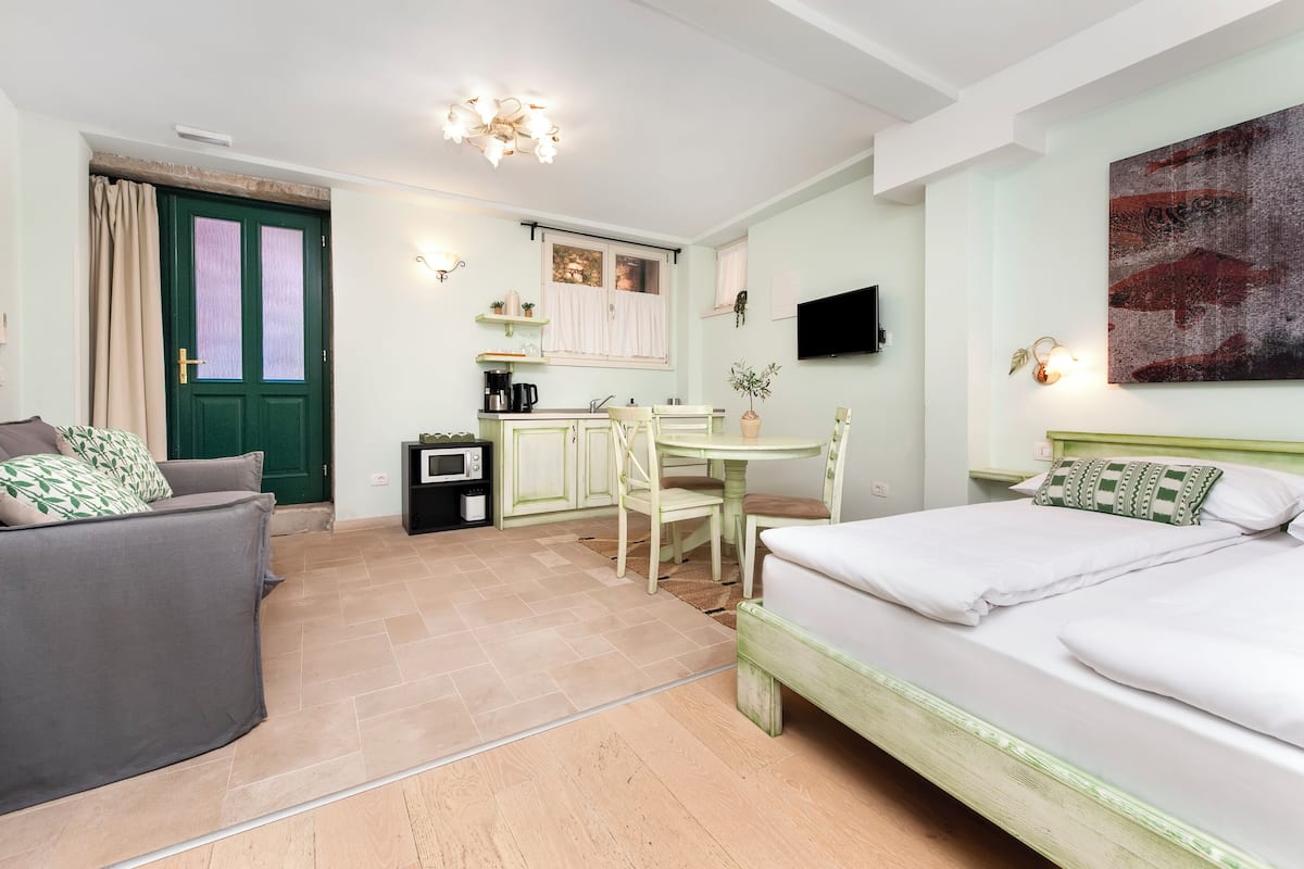 Une pièce de taille modeste comprenant un lit, un canapé, une table à manger et un coin cuisine.