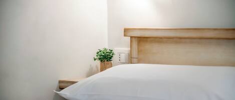 A neatly made bed with white linens and a wooden headboard.
