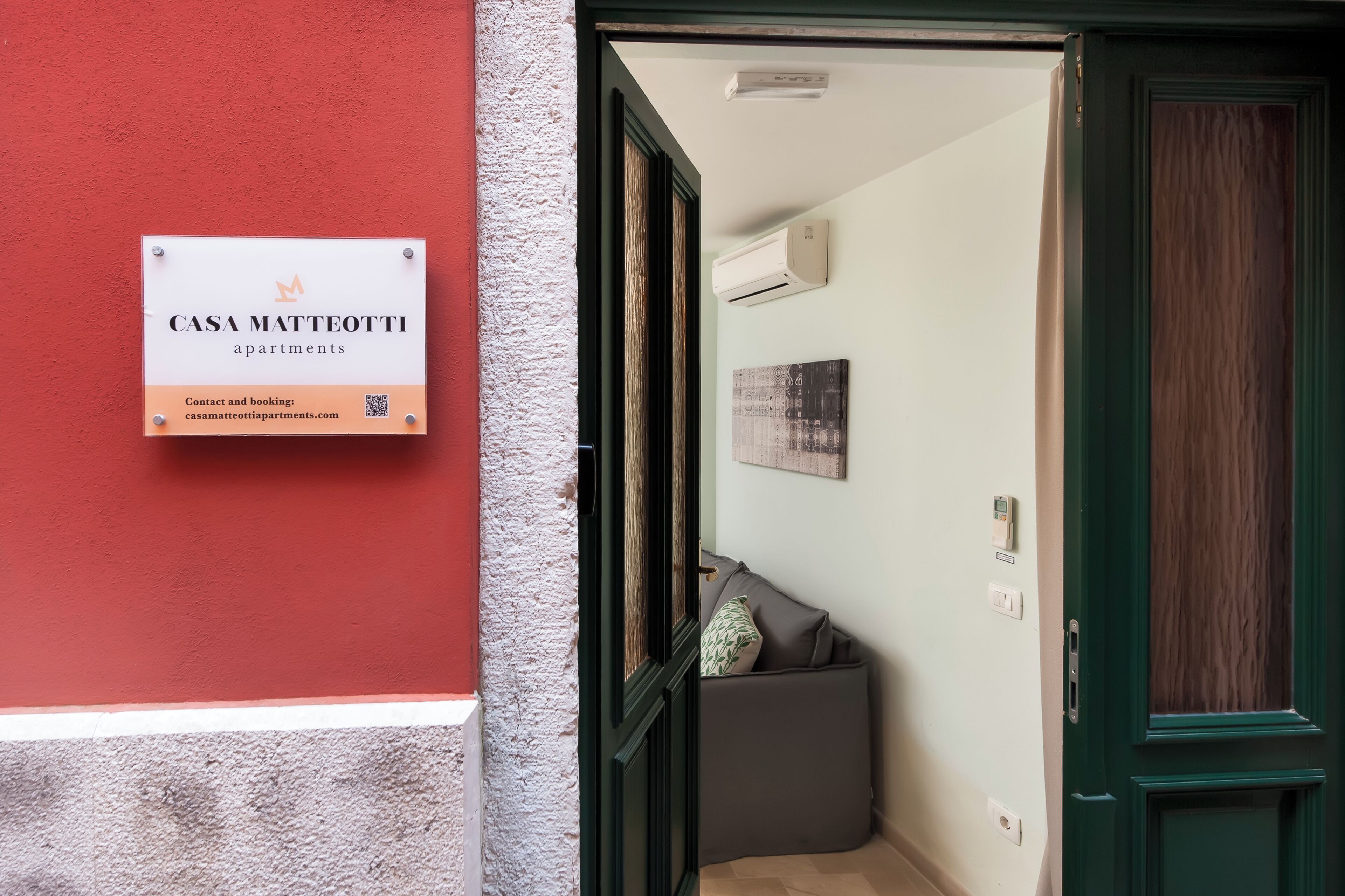 Une enseigne indiquant les appartements Casa Matteotti, avec les coordonnées et les informations relatives aux réservations.