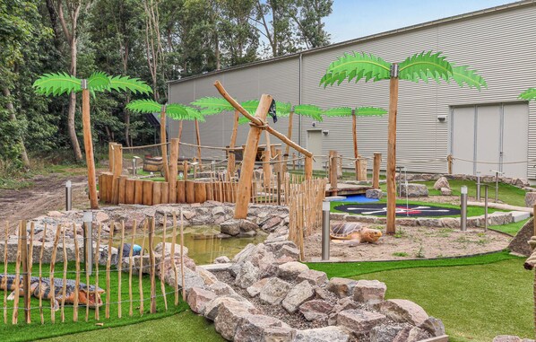 Explore the naturalistic wildlife viewing area with a water body, rocks, logs, and artificial palm trees.