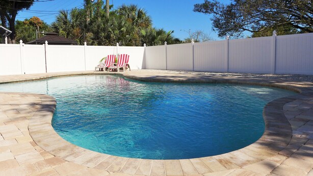 Ein Pool mit gewölbter Kante, umgeben von einem weißen Zaun, und eine kleine amerikanische Flagge.