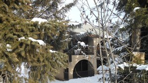 Ein schneebedecktes Gebäude mit Balkon und Bogenportal.