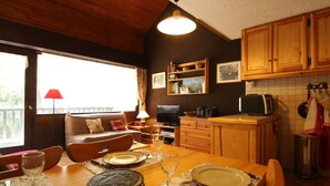 Eine gemütliche Küche mit Holzausstattung, einem Esstisch für Zwei und einem Fernseher in der Ecke.