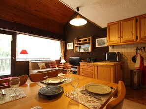 Eine gemütliche Küche mit Holzausstattung, einem Esstisch für Zwei und einem Fernseher in der Ecke.