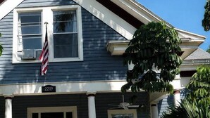 Une maison à deux étages avec un porche à l’avant, un drapeau et une boîte aux lettres.