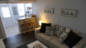 Un salon avec un canapé, une table basse et, au fond, un coin cuisine.