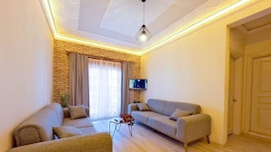 A living room with two sofas, a coffee table, and a TV mounted on the wall.