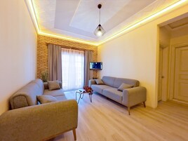 Una sala de estar con dos sofás, una mesa de centro y un televisor montado en la pared.