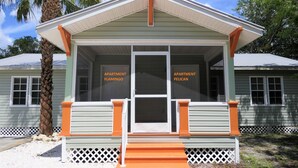 A two-story building with a porch, labeled 'Apartment Flamingo' and 'Apartment Pelican'. - Sun, beach, and great savings: huge discounts on holiday destinations! (Fort Myers)