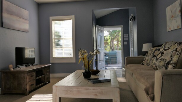A living room with a TV, a coffee table, a sofa, and a door leading to an outdoor area. - Sun, beach, and great savings: huge discounts on holiday destinations! (Fort Myers)