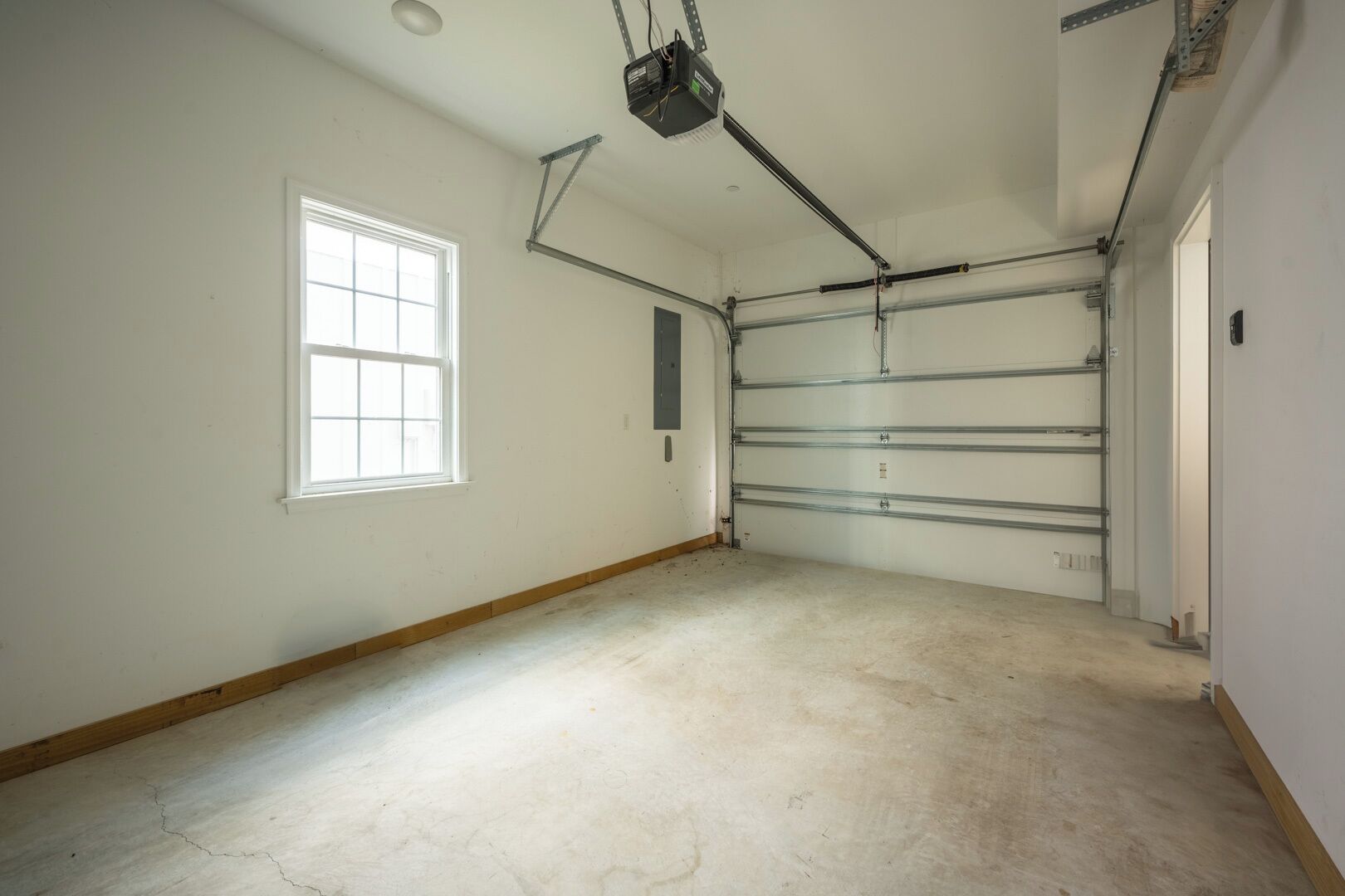 A room with a large garage door, a window, and a ceiling-mounted projector.