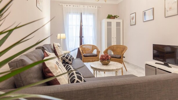 A living room with a sofa, two wicker chairs, a small table with a bowl, a TV, and a cabinet. - Elegant 2 BR in the heart of Seville.A / C / WIFI AV (SEVILLA)