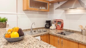 A kitchen with granite countertops, stainless steel appliances, wooden cabinets, a built-in oven, and a clock on the wall. - Elegant 2 BR in the heart of Seville.A / C / WIFI AV (SEVILLA)