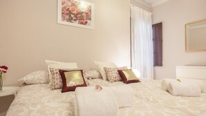 A hotel room with a large bed, two pillows, a vase with flowers, and a framed picture on the wall. - Elegant 2 BR in the heart of Seville.A / C / WIFI AV (SEVILLA)