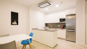 Una cocina moderna con una isla central, electrodomésticos de acero inoxidable y una paleta de colores blanca.