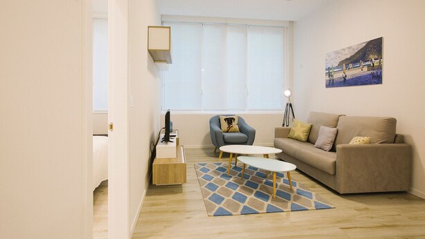 Una sala de estar moderna con un sofá, una silla, una mesa de centro y un cuadro en la pared.