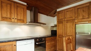 A kitchen with wooden cabinets, a stainless steel refrigerator, a dishwasher, and a microwave. - Spacious, Bright 3*** Apartment with WIFI (La Clusaz)
