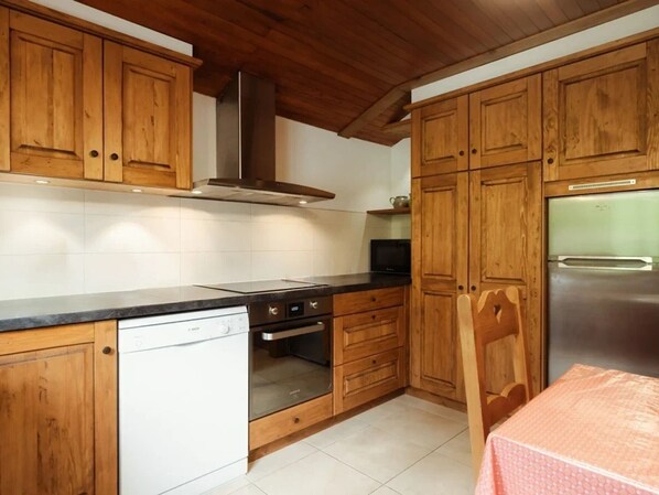 A kitchen with wooden cabinets, a stainless steel refrigerator, a dishwasher, and a microwave. - Spacious, Bright 3*** Apartment with WIFI (La Clusaz)