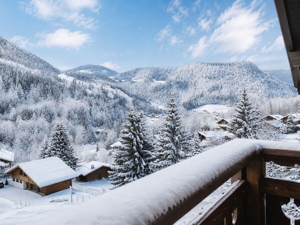 A snowy mountain landscape with cabins and a wooden balcony railing. - Spacious, Bright 3*** Apartment with WIFI (La Clusaz)