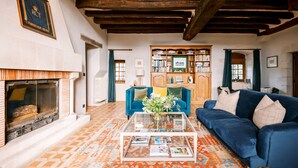 A cozy living room with a fireplace, a blue sofa, a coffee table, and a bookshelf.