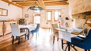 A spacious dining area with wooden beams, a stone wall, and a large window.