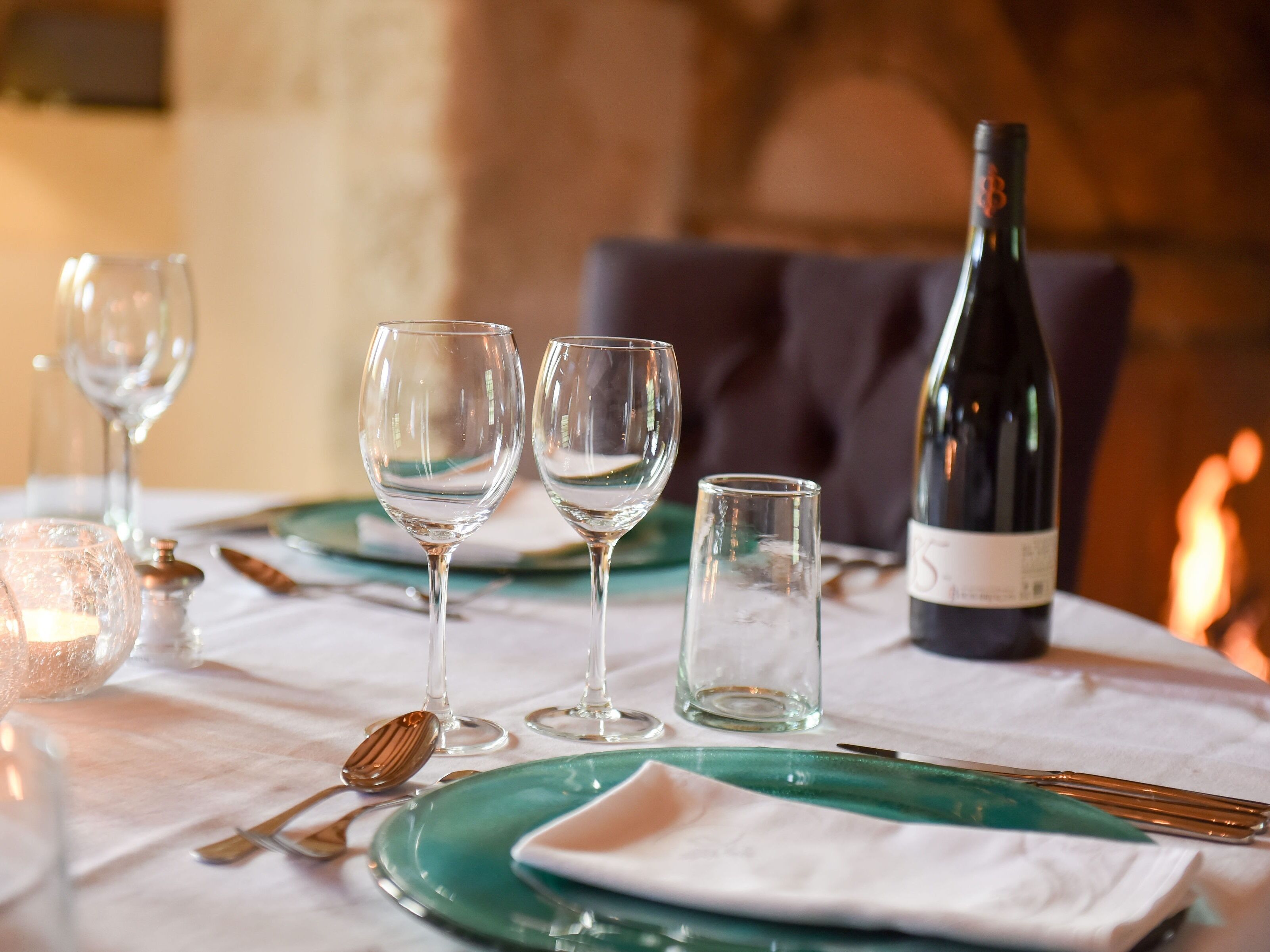 A table set for dining with wine glasses, a bottle, and cutlery.