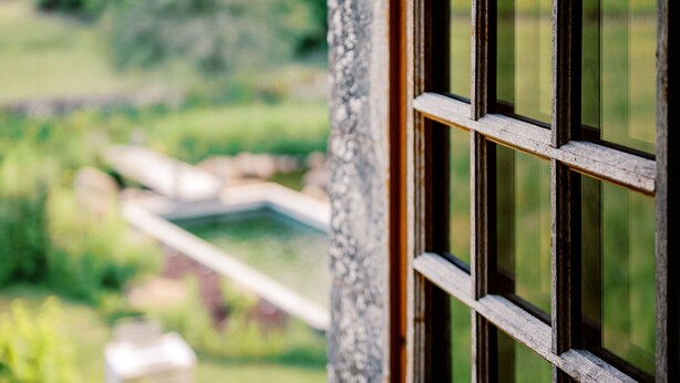 A close-up of a wooden window frame with a blurred outdoor view.