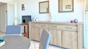 Ein modernes Wohnzimmer mit Essbereich, einem Fernseher und einer Vitrine mit Dekorationen.