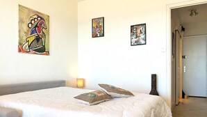 Ein Hotelzimmer mit einem großen Bett, zwei Kissen, einem Nachttisch und drei Bildern an der Wand.