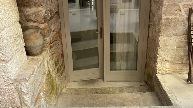 A stone-walled entrance with a glass door and a lantern above.